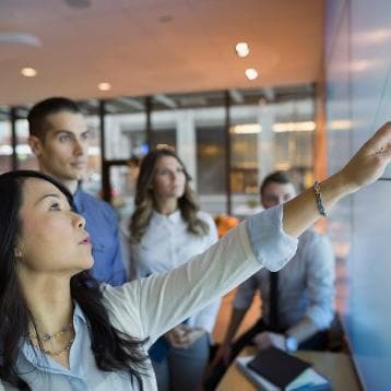 Coworkers looking at data on large screen