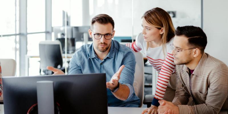 Meeting of three people at a computer Three people in a meeting at a computer