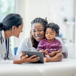Doctor speaking with young patient and mother