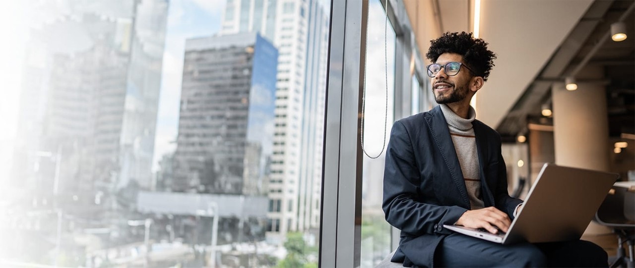 Business man working on a laptop and looking out a window