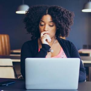  Woman sitting with a concentrated look at an open laptop computer